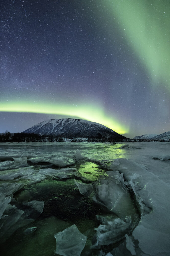Snow-covered mountains glowing under polar light during winter in the Lofoten Islands, Norway