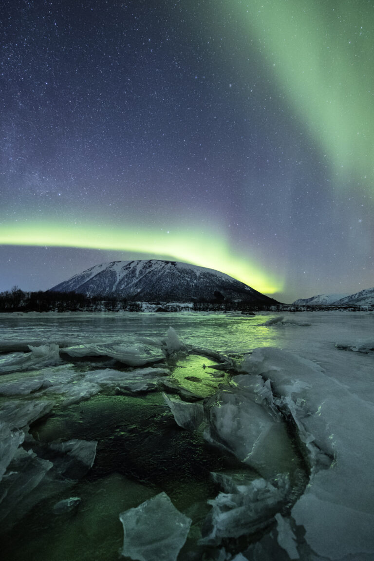 Snow-covered mountains glowing under polar light during winter in the Lofoten Islands, Norway